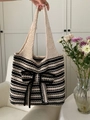 Detail einer gestreiften Stricktasche mit großer Schleife und weicher Webstruktur - Schwarz