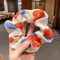 Dettaglio di scrunchie bianco a fiori rossi e blu con trama di tessuto arricciato - Fiore Arancione