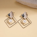 Orecchini geometrici in argento con perle pendenti su superficie beige testurizzata - Stile Perla Geometrica con Perno in Argento / Argento