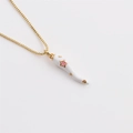 Macro detail of gold-plated chili pendant with white horn and small pink star - White