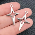 Set di due ciondoli a stella in argento lucido con design a quattro punte traforate - 15x25mm / Argento Antico