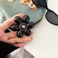 Close-up of black floral phone grip with golden heart center on denim background - Black