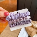 Détail de 3 chouchous violets avec imprimé léopard et texture satinée sur carte cadeau - Violet + Violet Clair + Léopard Violet / Ensemble Violet