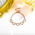 Detalle de los dijes de corazón hueco en una pulsera de eslabones de acero inoxidable - Oro de 18K / Oro rosa