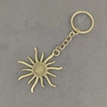 Vintage Bronze Schlüsselanhänger mit Sonnenanhänger auf grauem Hintergrund aus Beton - Antike Bronze Sonne