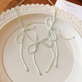 Detail der mintgrünen Perlenkette mit drei Schleifen auf einem eleganten Keramikteller - Grüne Schleife Halskette