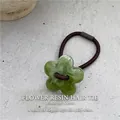 Primer plano de flor de resina jaspeada verde en una goma de pelo elástica marrón - Verde