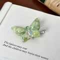 Elegante pinza de mariposa verde con pedrería mostrada sobre un libro abierto - Pinza para el cabello / Verde