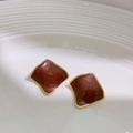 Brown enamel square stud earrings with golden edges shown on a white textured plate - Coffee