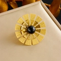 Elegante anello a fiore dorato con petali testurizzati e gemma nera su porta gioielli - Anello con zircone nero (R490)