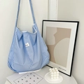 Close-up of blue striped fabric tote bag with aesthetic est. ADORE woven label detail - Blue Stripe