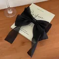 Detalle de un lazo para el pelo en organza negra sobre una página de libro artístico - Negro