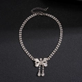 Detailed macro view of silver bow pendant with crystal teardrop tassels on double chain - Bowknot Tassel Necklace / Silver
