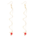 Detail of gold spiral drop earrings featuring elegant red pearls and French hooks - Red Bead Spiral Earrings / Red