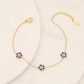 Detailed close-up of gold stainless steel flower bracelet with purple evil eye charms - Royal Blue