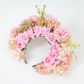 Dettaglio di rose rosa e ortensie pesca su un cerchietto floreale con foglie verdi - Rosa