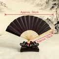 Classic black Japanese folding fan with bamboo ribs on a vintage wooden display stand - Single-Sided Black Fabric