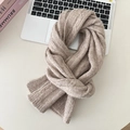 Detailed flat lay of a chunky knit wool scarf in soft beige on a minimalist desk - Apricot