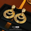 Pendientes de espiral dorados con aros entrelazados sobre joyero negro de lujo - Dorado
