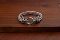 Detail of silver wolf head bracelet with braided steel chain on wooden surface - Wolf Head