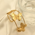 Macro-opname van de vergulde roestvrijstalen vlinderarmband op zijden achtergrond - Gouden Vlinder Dubbele Ring Open Armband