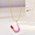Detail of U-shaped enamel necklace in pink and white on golden chain over stone - Letter U