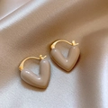 Close-up of golden hoop earrings with beige heart-shaped enamel charms on silk fabric - 10# Beige Heart Enamel Ear Clip