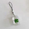 Detail of transparent resin rectangle charm with real green four-leaf clover inside - Square Clover / Phone Strap