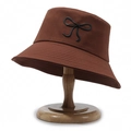 Brown cotton bucket hat with black bow embroidery on a wooden stand for sun protection - Coffee