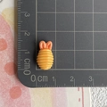 Miniatur Spirale aus gelb-rosa Kunstharz auf einer Skalmatte zur Größenbestimmung gezeigt - Frittiertes Hähnchen-Nugget