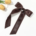 Close-up of a coffee brown satin bow hair clip with ruffled edges and long streamers - Brown