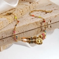 Golden beaded Tree of Life bracelet with colorful charms on a stone and silk background - Tree of Life Style