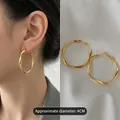 Professional view of 4CM gold twisted geometric hoop earrings on a model and silk fabric - Medium / Twisted Hoop Style (42) / Gold