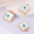 Goldene quadratische Evil Eye Anhänger mit weißer Basis und Türkis auf lila Hintergrund - Quadratisch