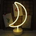 Moon-shaped neon LED night light with white base and warm yellow glow on a wooden desk - Warm White Moon