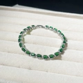 Detailed shot of a silver tennis bracelet with green oval zircon in a jewelry box - 18K Gold / Green Zirconia White Gold