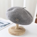 Detail of grey wool beret with golden metal rings on a wooden stand in a cozy setting - M (56-58cm) Adjustable / Heather Grey