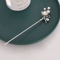 Detail of silver floral hair stick with pearls on a dark green decorative plate - Pearl Flower
