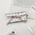 Pochette argentée matelassée en cœur avec nœud rose et dragonne sur un bureau - Style de cravate à rabat matelassé en forme de cœur / Argent