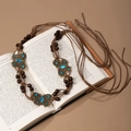 Detail of bohemian waist chain with bronze butterflies, blue gems and wooden beads on book - Bronze Butterfly Blue Gemstone Woven Belt (X451-20)