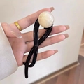 Eleganter schwarzer gedrehter Haarclip mit einer großen weißen Perle in der Hand - Transparent Beige