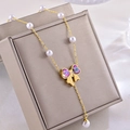 Vue macro d'un collier doré avec accents de perles et pendentif papillon en cristal coloré - Collier