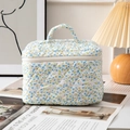 Borsa per trucco trapuntata con motivo floreale blu e maniglia in un ambiente accogliente - Fiorito Blu (Grande)