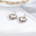 Macro view of silver heart charms with pavé set crystals and polished inner surface - Zircon Heart / Silver