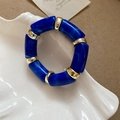 Macro detail of blue marble acetate segments and gold spacer beads on elastic bracelet - Blue