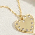 Macro shot of gold heart pendant featuring polished surface and sparkling zircon border - Heart Zirconia Style (XL2690-6)