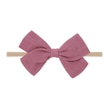 Detail of a soft pink fabric bow on a beige elastic nylon baby headband on white background - Pink