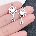 Vintage silver heart-shaped key charms for DIY jewelry making shown on a fingertip - Peach Heart Shaped Key (4162)