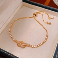 Primer plano de una pulsera dorada con nudo de circonitas en una elegante caja de regalo - Cierre Deslizante Ajustable (HB1663) / Dorado