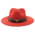 Detail of red straw fedora hat featuring a brown leather band and silver bull head emblem - Red